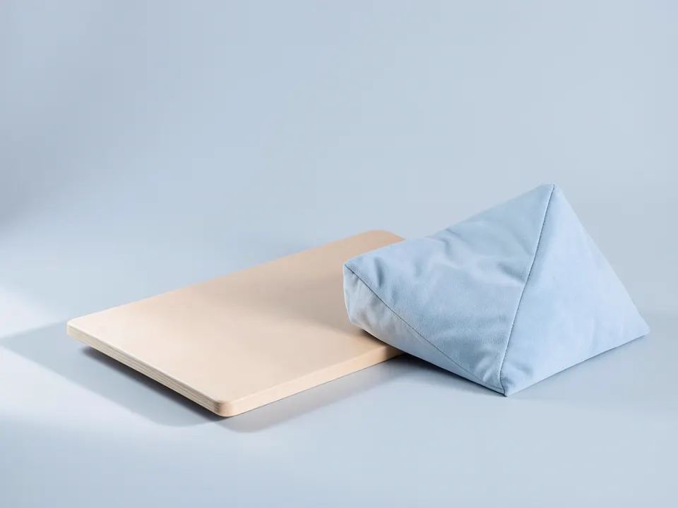 Wooden transfer board beside a wedge positioning pillow
